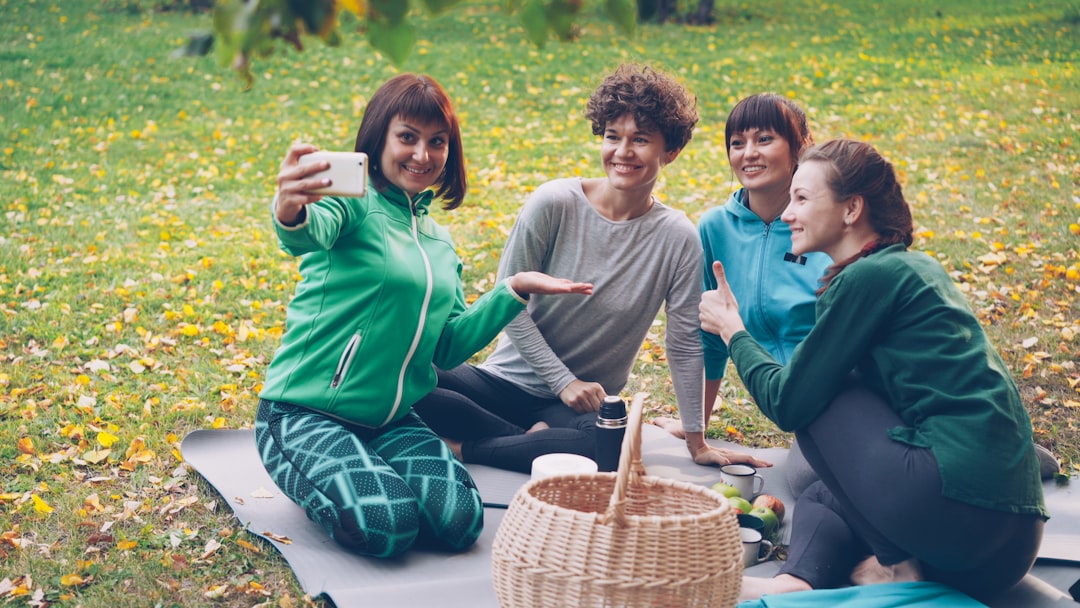 Friends enjoying outdoor self-care picnic and yoga session in Brooklyn park during fall.